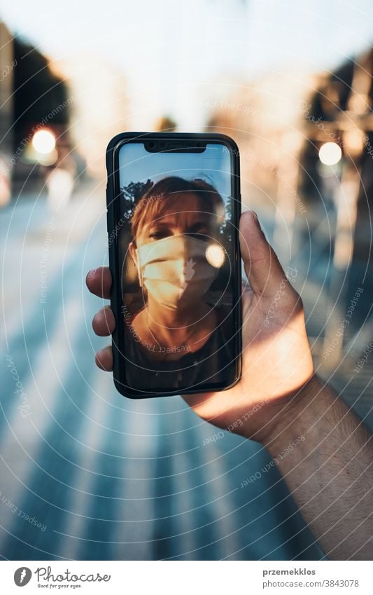 Young man having video call talking while walking downtown wearing the face mask to avoid virus infection care caucasian chat contagious corona coronavirus