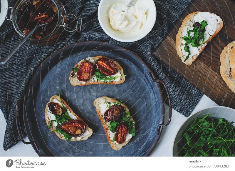 italian traditional bruschetta - bread toast with sun dried tomatoes, cream cheese, olive oil and arugula. sandwich food snack vegetable healthy herb appetizer