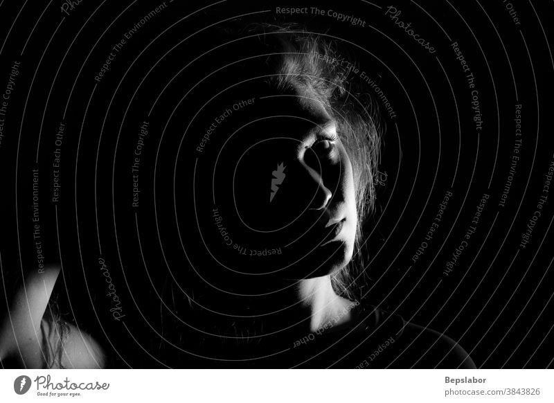 Black and white portrait of an Italian girl on black background dramatic tension beautiful sensual dark sadness illuminated obscure black and white gloomy