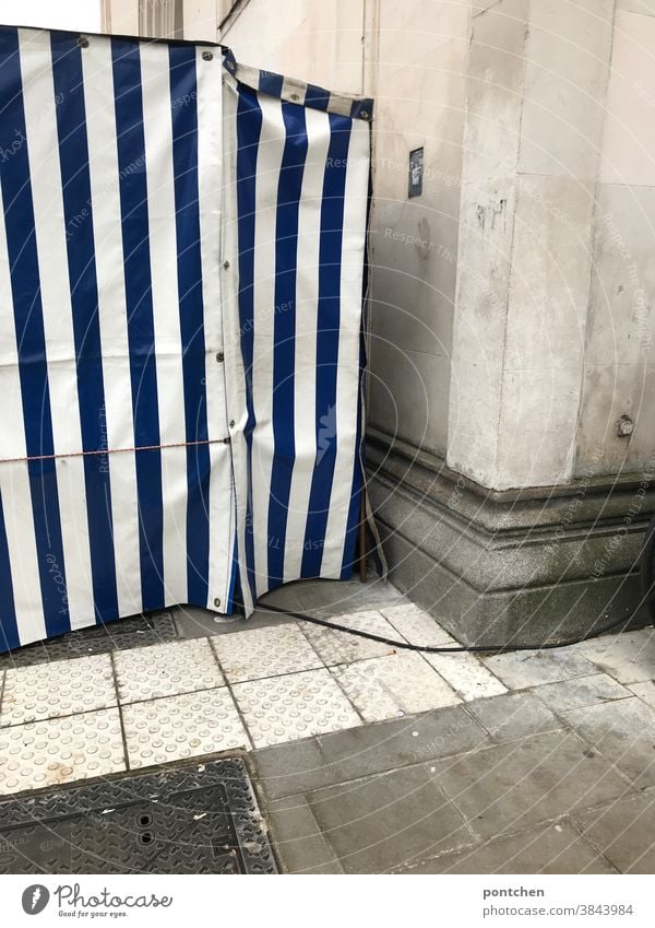 A blue and white striped fruit stand from the side. Tarpaulin, tent, Observations tarpaulin plastic Tent Stripe power cable Pattern Covers (Construction)