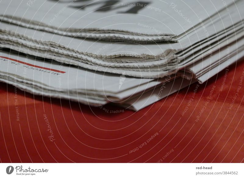 Close-up of a daily newspaper, upper edge, red background, only one corner and fold visible Newspaper Daily newspaper Stack of paper White Red
