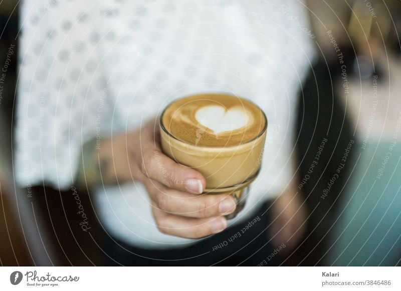 Glass of latte with latte art heart in hand of woman with white blouse Latte macchiato Heart milk foam barista latte type Espresso Breakfast Coffee Café