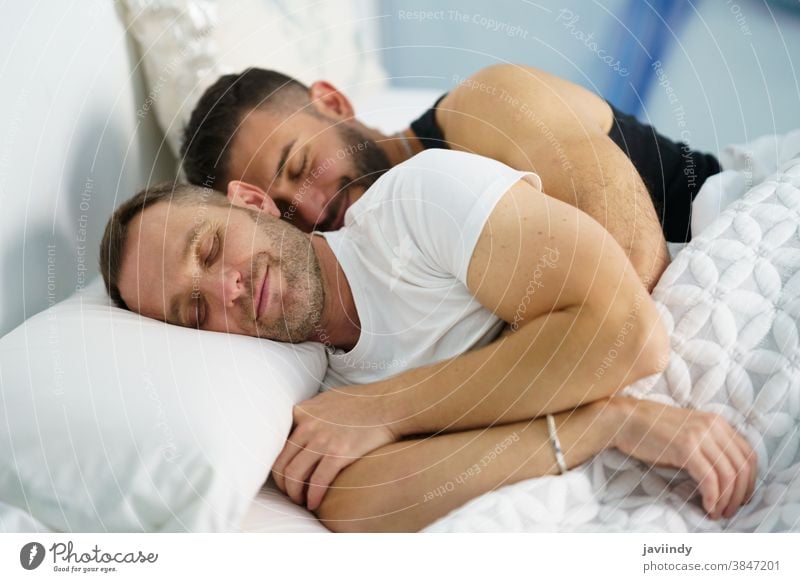 Gay couple sleeping in each other's arms. gay men homosexual bed lgbt love lgbtq male relationship lovers boyfriend people 30s togetherness caucasian hispanic