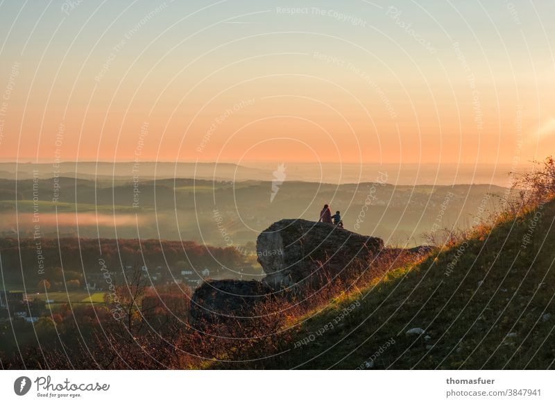 Couple sitting on a rock looks into the distance and watches the sunset Beautiful weather Sunday Autumn Sky colors mountain Mother Child Sunset Nature Landscape