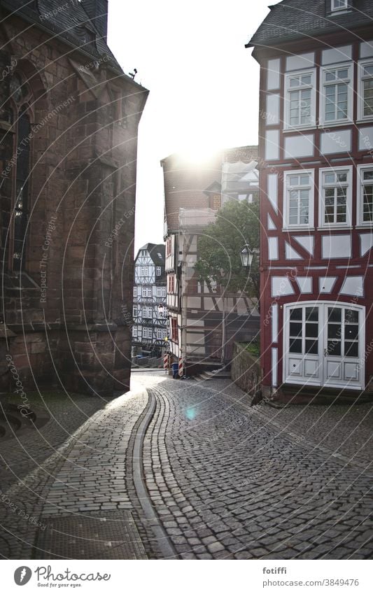 Alley in Marburg against the light Back-light Cobblestones Street Half-timbered facade Half-timbered house Old town Sunlight Exterior shot Deserted Historic Day