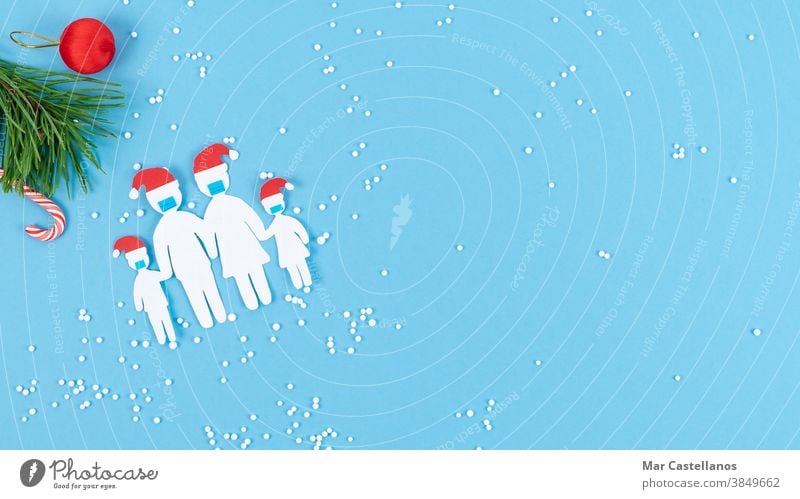 Family cut out of paper with mask and Christmas hat on a blue background. Copy space. family decoration christmas hat snow love united copy space children