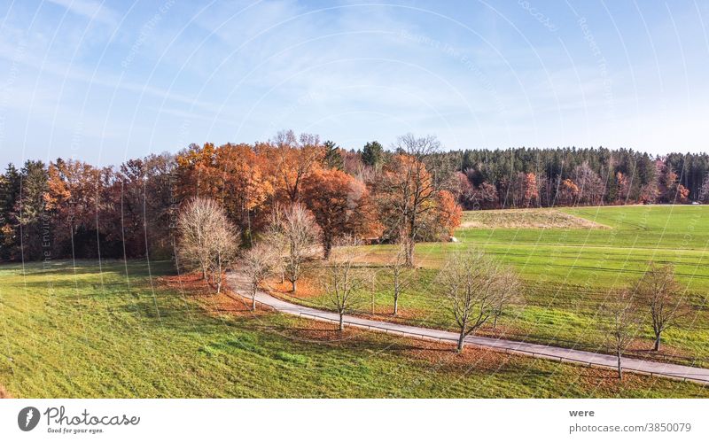 View from above over autumnally colored trees and the foothills of the Alps Area flight Autumn Windach Wooden park bench aerial view autumn color autumn forest