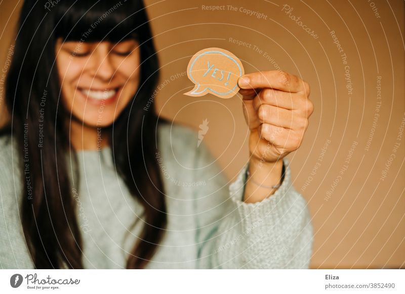 Laughing woman holding a speech bubble with the word "yes" in English Yes Laughter Positive Affirmative Joy Good mood Success successful feeling of happiness