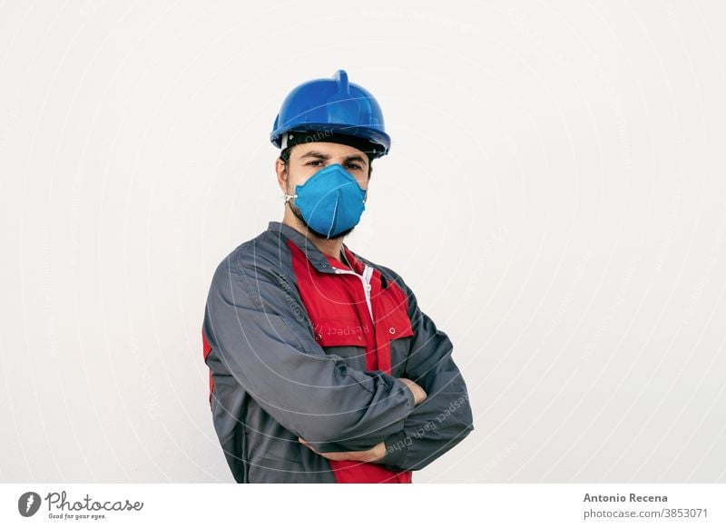 Attractive worker man with face mask for protection looks at camera covid-19 uniform security pandemic virus white background wall coronavirus surgical mask