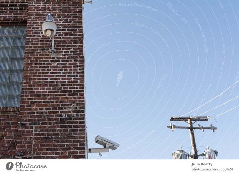 Security camera, powerlines, and industrial light on brick warehouse building security big brother Surveillance Surveillance camera Monitoring monitor Safety