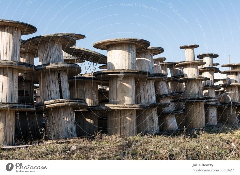 Wooden spools, cable reels, stacked up for storage in an industrial park wooden spool old pile wood slat vintage retro worn metal architecture sky container