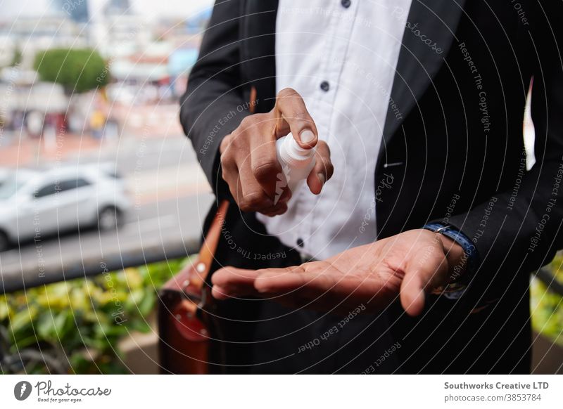 Close Up Of Businessman Spraying Hands With Sanitiser During Health Pandemic business businessman office worker sanitizer hand sanitizer sanitizing dispenser