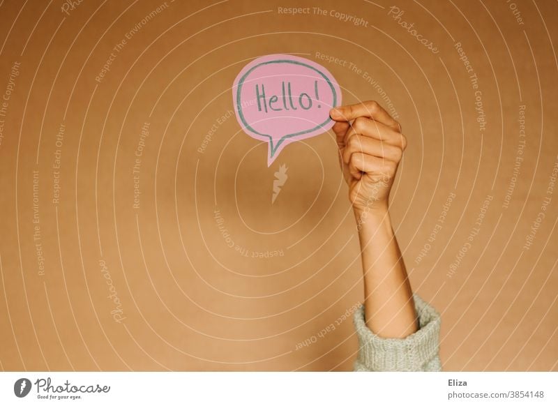 Hand holds a speech bubble in which Hello! stands. Greetings in English. salute sb. Speech bubble hello Foreign language Communicate Language communication Hi