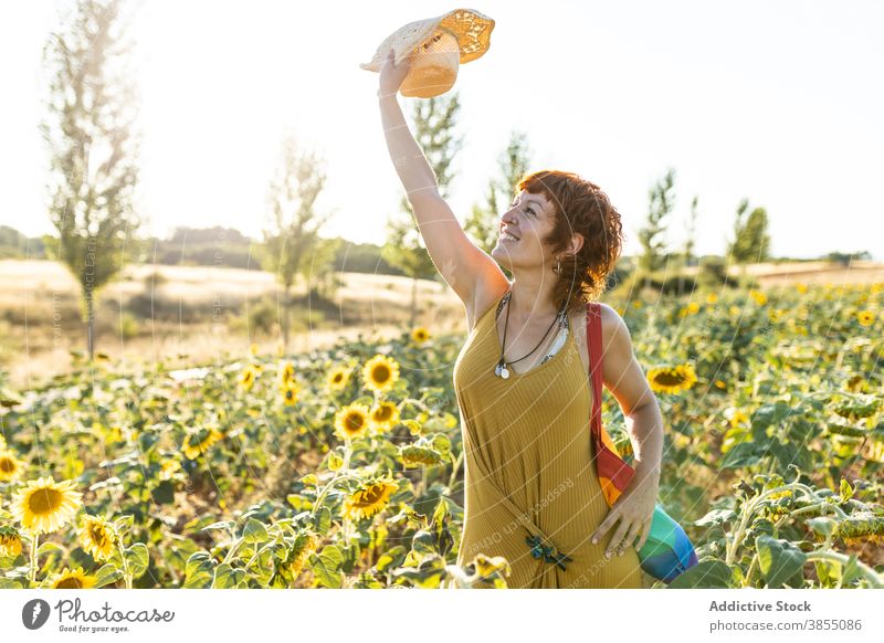 Tranquil woman relaxing in sunflower field enjoy nature bloom season sunny carefree female rainbow bag stand calm weather tranquil peaceful freedom serene lady