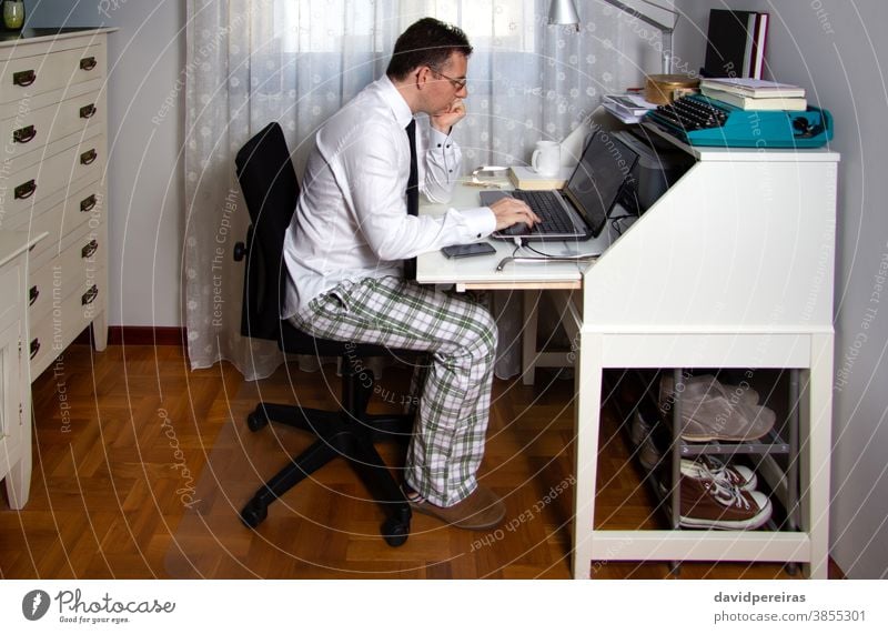 Man teleworking wearing shirt, tie and pajama pants working from home coronavirus epidemic quarantine telecommuting social distancing laptop internet technology