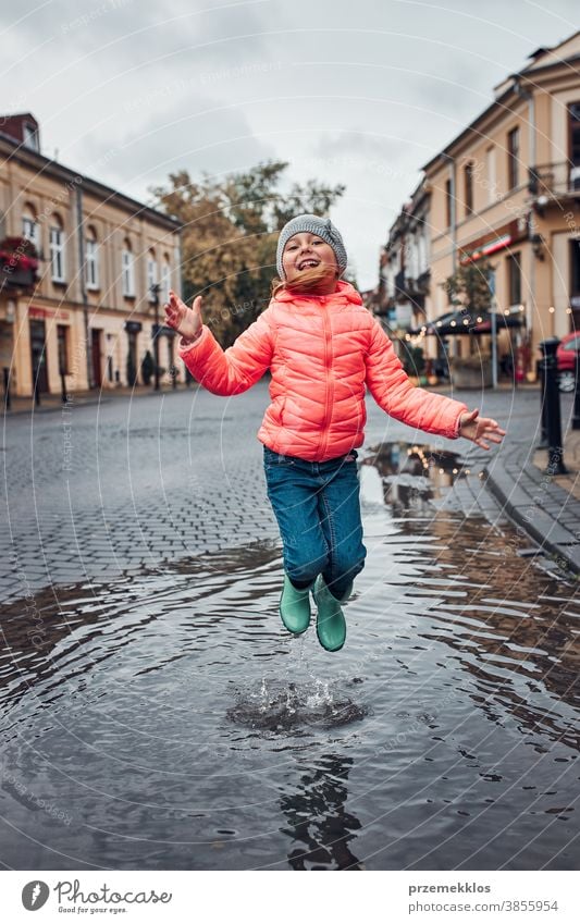 Little girl jumping in the puddle on rainy gloomy autumn day raining outdoors little seasonal fall childhood beautiful weather outside kid wet holding city town