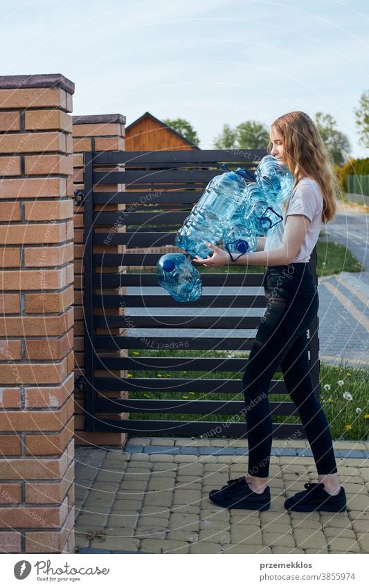 Young woman throwing out empty used plastic water bottles into trash bin blue collect collecting container crushed disposal ecology environment female garbage