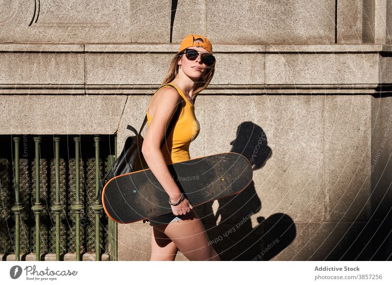 Young hipster female skater on city street woman teenage skateboard urban trendy ride summer style hold lifestyle modern contemporary young activity cool