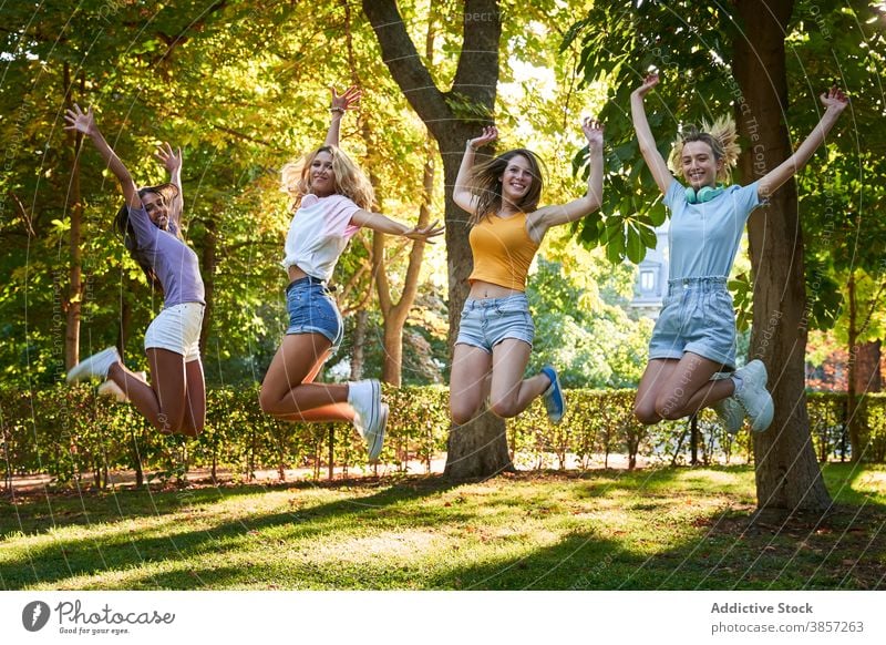 Group of diverse teen girlfriends jumping high in park having fun summer happy cheerful together teenage women multiracial multiethnic female friendship