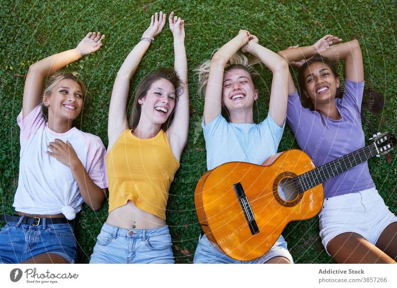 Happy multiracial teenagers with guitar enjoying summer day in park girlfriend chill lying happy cheerful together rest women multiethnic diverse female