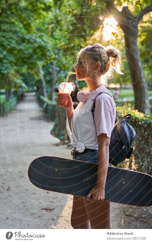 Young woman with skateboard and milkshake in park drink summer rest hipster teen enjoy female skater teenage lifestyle young trendy cool relax millennial