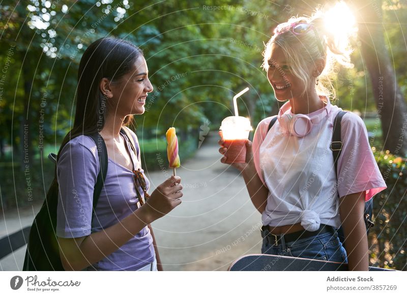 Happy girlfriends with ice cream and drink having fun in park summer popsicle happy cheerful chat together diverse multiethnic multiracial teen female