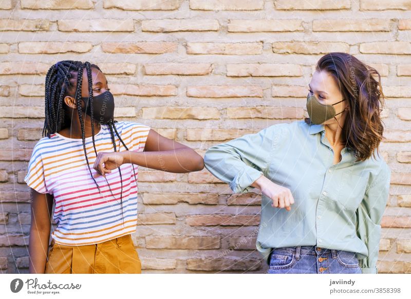 Multiethnic young women wearing masks greeting at each other with their elbows people social distancing woman pandemic virus coronavirus lifestyle covid