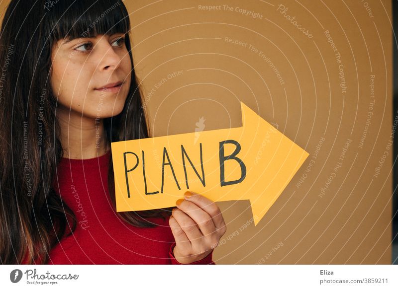 A young woman holds a yellow arrow with the inscription PLAN B. Alternative life path. Plan B alternative path of life Direction solution Planning Business