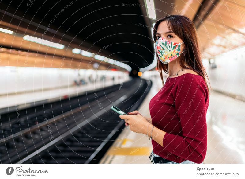 Young woman using smartphone at train station portrait mask face lifestyle platform modern public technology transport caucasian passenger people transportation