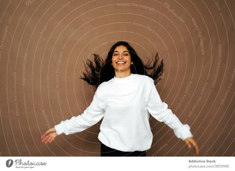 Delighted woman with flying hair in studio having fun laugh white sweatshirt casual style cheerful female ethnic enjoy modern positive young fashion delight