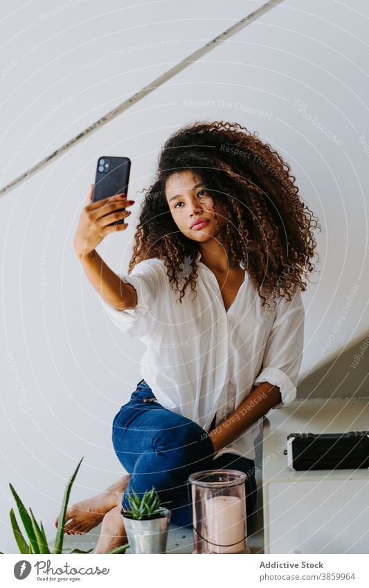 Stylish ethnic woman taking selfie at home smartphone style afro curly hair photography modern young female black african american mobile device gadget