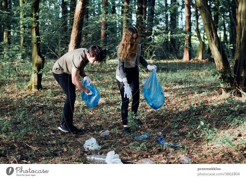 Young man and woman cleaning up a forest. Volunteers picking plastic waste to bags activist bottle care child collect concept ecology environment garbage girl