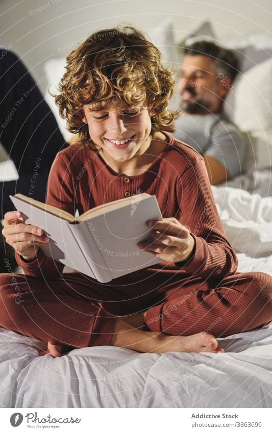 Cute child reading book in room bedroom kid clever entertain father son interesting home story joy literature sit comfort together childhood cozy education
