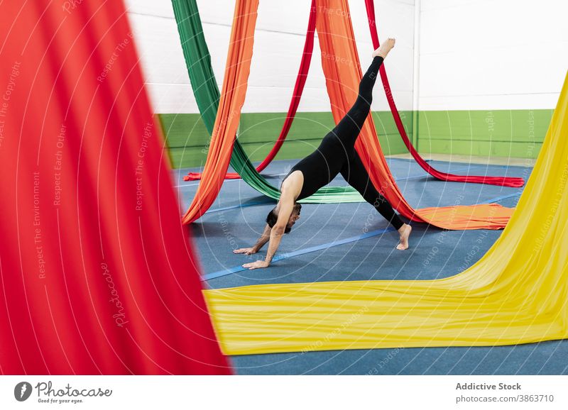 Barefoot man exercising near aerial silks dancer exercise gymnastic leotard balance rehearsal practice male barefoot floor cloth colorful flexible perform