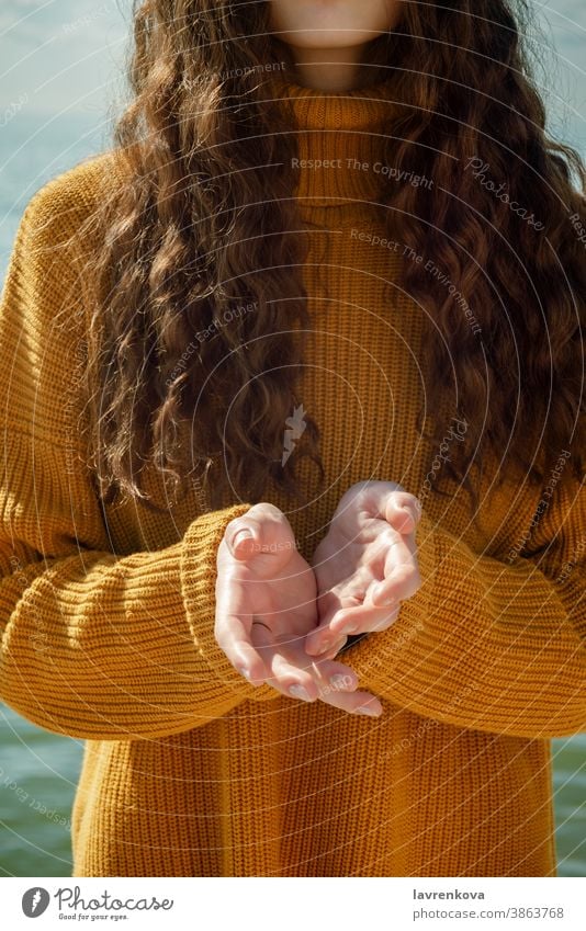 Faceless portrait of woman on a beach stretching forward out her hands female sweater closeup palms asking concept hold giving faceless carrying fingers empty