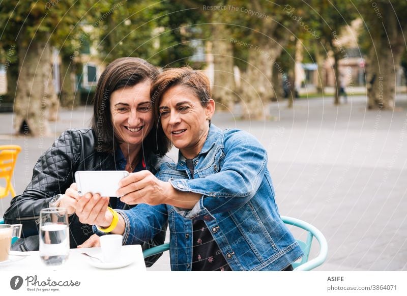 Middle aged lesbian couple taking a selfie LGBTQ gay middle aged 40 50 smart phone self portrait mobile phone smile homosexual women real people candid love