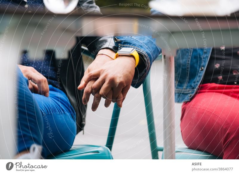 Lesbian couple holding hands under the table lesbian LGBTQ gay middle aged 40 50 mid section hiding homosexual women real people candid love girlfriend family