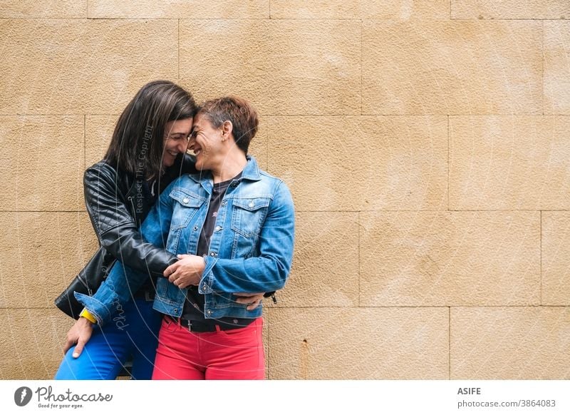 Happy middle aged lesbian couple hugging outdoors LGBTQ gay 40 50 holding embrace laughing smile nose homosexual women real people candid love girlfriend family