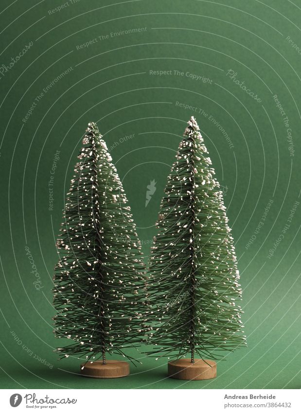 Two fir trees with snow on a green paper background, space for text on top creative traditional snowflake minimal trendy greeting copy space template