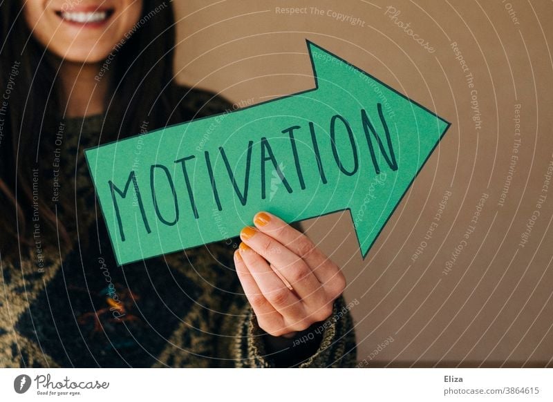A woman holds a green arrow with the inscription Motivation Motive motivate laud acknowledgement Woman Profession Arrow Orientation Future Career Success Target