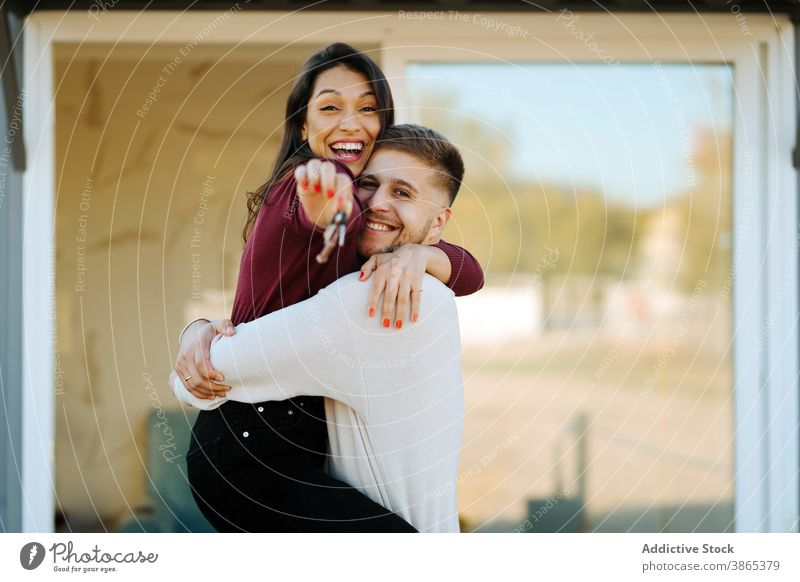 Excited couple with keys from new house real estate excited hug homeowner together embrace smile cheerful relationship property enjoy happy positive affection