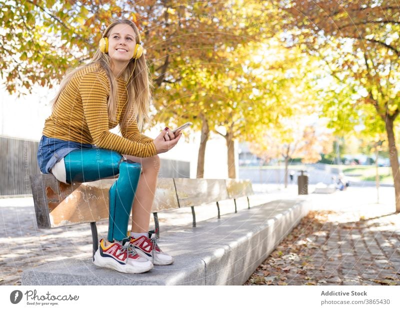 Cheerful woman with leg prosthesis listening to music in headphones bionic street city enjoy female song amputee sunny relax device happy cheerful smartphone