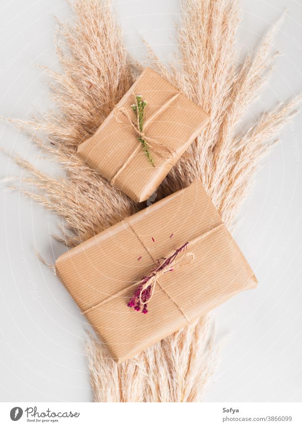 Gift boxes wrapped in craft paper with dried flowers autumn gift zero birthday christmas background give surprise present concept waste pampas stack grass