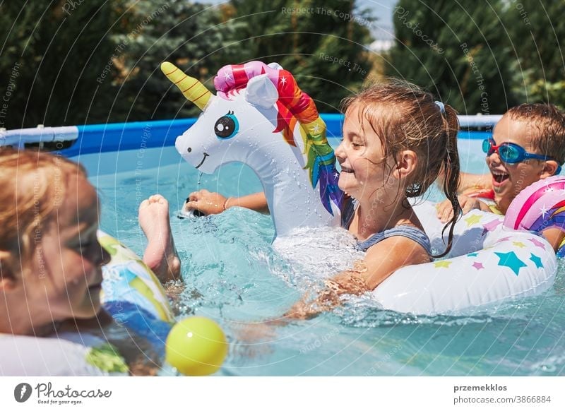 Children playing in a pool in a home garden. Kids having fun playing together on a summer sunny day authentic backyard childhood children family happiness happy