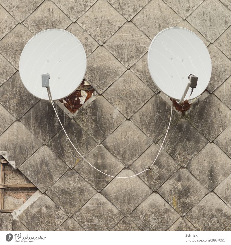 Two parabolic antennas in a dirty facade made of asbestos fibreboards remind of a pair of ears Parabolic antennas 2 Couple find out facade panels