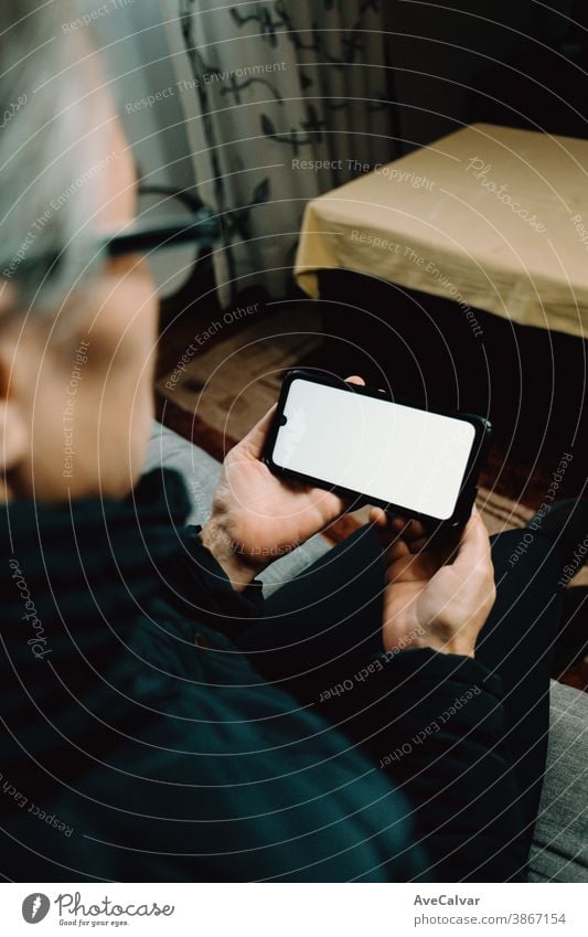 Old woman watching a phone with a white screen with copy space in a living room person elderly grandmother copyspace mature senior happy older retired