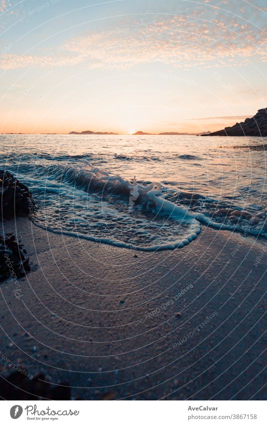 Vertical image of a tide on the beach over the sand during a colorful sunset with the islands as the background and copy space ocean wave sunrise gold surf