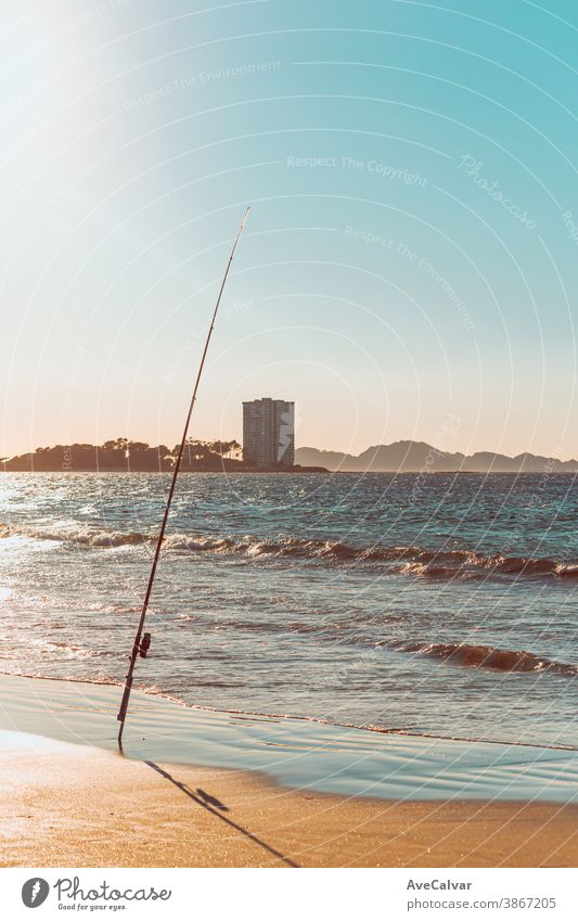 Fishing rod in a beach in front of a massive building during a