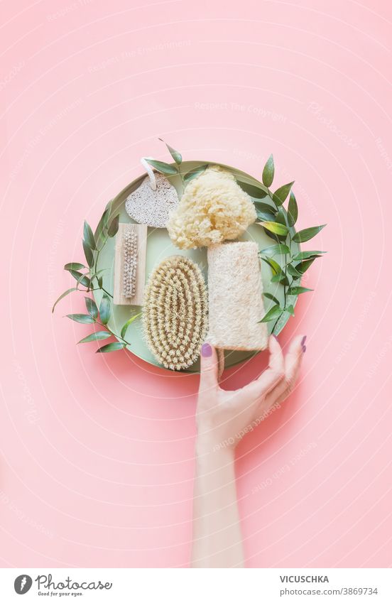 Women hand holding eco friendly beauty and skin care bathroom accessories.  Natural sisal brush, wooden comb, soap, reusable make up removal pads. Zero waste. Top view. Natural and pastel colors.