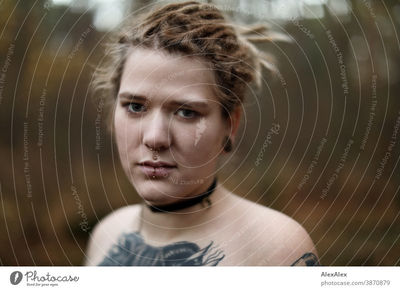 Portrait of a young woman with dreadlocks and tattoos in the forest Woman Dirty Blonde tattooing Jewellery Piercing earring décolleté Upper body Naked Concealed